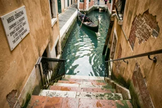 Escaliers en pierre à Venise descendant vers le canal avec panneau d'interdiction de s'asseoir affiché sur le mur