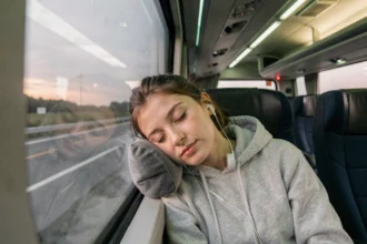 Passagère endormie dans un bus BlaBlaBus avec oreiller de voyage contre la fenêtre